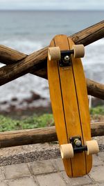 Close-up of skateboard on railing against sea