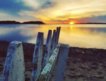 Close-up of wooden posts in lake against sky