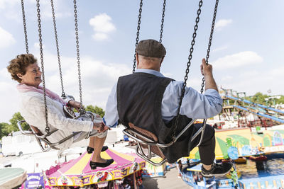 Senior couple hand in hand on chairoplane at funfair