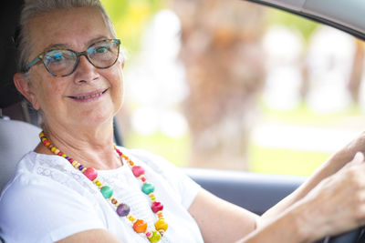 Portrait of smiling senior woman sitting in car