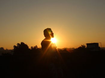 Silhouette man standing by tree against sky during sunset