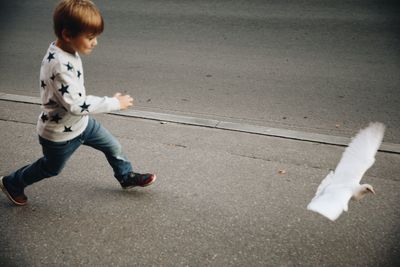 Full length of boy walking on road in city