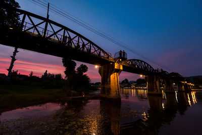 Bridge over river against sky at sunset