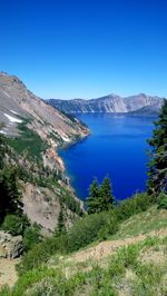 Scenic view of lake and mountains against clear blue sky