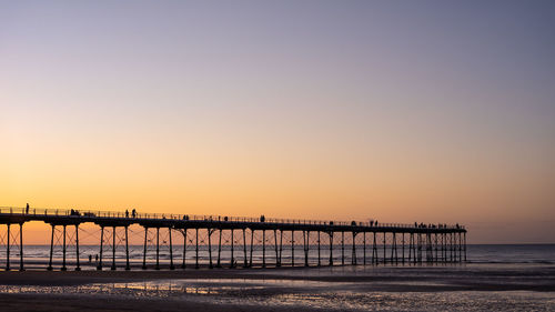 Pier over sea against clear sky during sunset