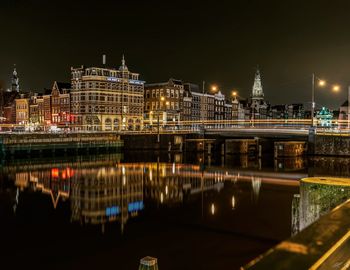 Illuminated bridge over river in city at night