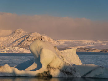 Scenic view of sea and snowcapped mountain against sky during winter