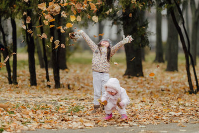 Full length of woman with leaves on field during autumn