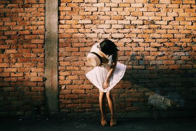 Full length of woman standing against brick wall