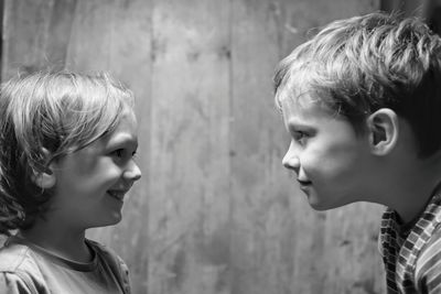 Close-up of brothers face to face against wall