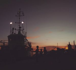 Silhouette boat at harbor against sky during sunset