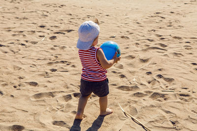 Child in a t-shirt and shorts walks on the beach near the sea