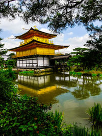 Traditional building by lake against sky