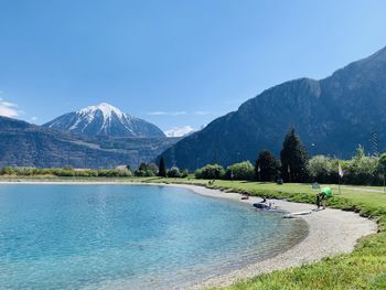 Scenic view of lake and mountains against blue sky