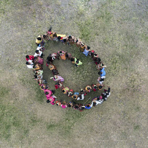 Directly above shot of people standing in spiral shape on field