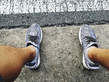 Low section of man standing on zebra crossing