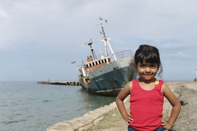 Portrait of girl standing at beach against sky