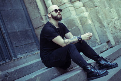 Thoughtful bearded bald man sitting on steps