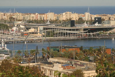 Bridge over river by buildings in city against sky