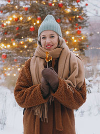 Portrait of young woman wearing warm clothing standing against trees