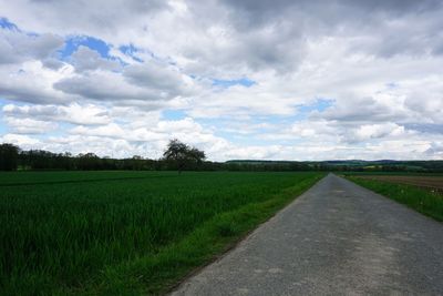 Road amidst field against sky