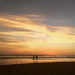 Silhouette man on beach against sky during sunset
