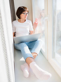 Young woman sitting on window sill