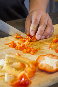 Cropped hands of man chopping red bell pepper on cutting board