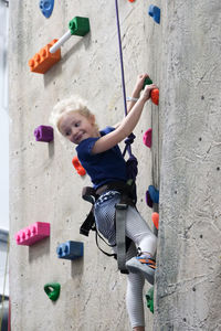 Young girl climbing rock wall at indoor rock climbing gym