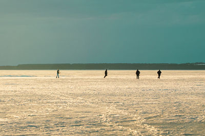 People on frozen lake against clear sky