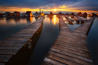 Pier over lake against sky during sunset