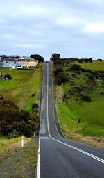 Road leading towards city against sky