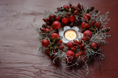 High angle view of berries by lit candle on table