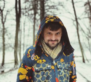 Portrait of mid adult man smiling while standing on snow covered field