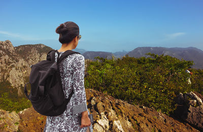 Woman traveller with a backpack standing on top of mountain.