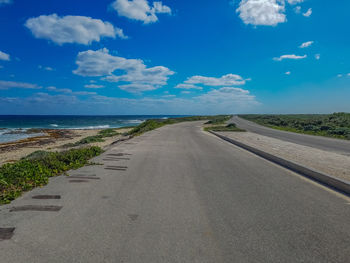 Road by sea against blue sky