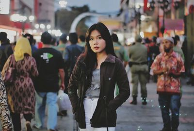 Portrait of woman standing on street in city during sunset