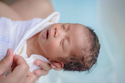 Cropped hands holding baby girl sleeping at home