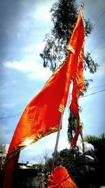 Low angle view of orange flags hanging against sky