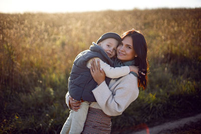 Fashionable sexy
brunette young woman stands in the autumn on the field with her son child