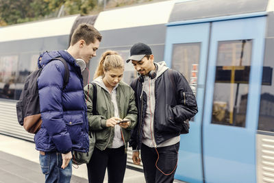 Multi ethnic university students using mobile phone at subway station