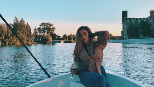 Portrait of woman sitting on boat in lake against sky