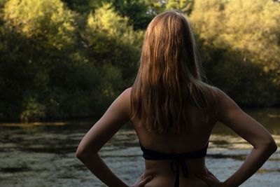 Rear view of woman standing by river