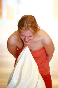 Young woman laughing while standing by sculpture