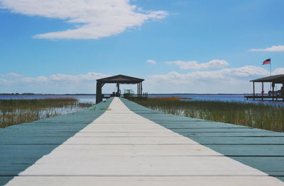 Boardwalk on beach against blue sky