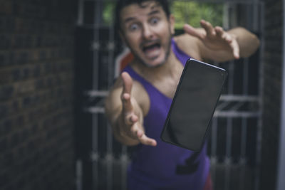 Portrait of man diving to reach his dropped mobile phone, outdoors.