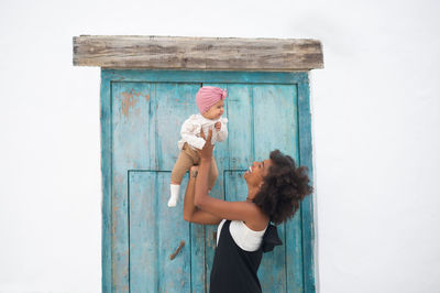 Side view of woman standing against door