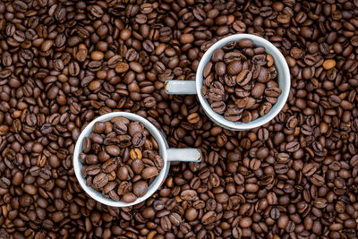 Close-up of roasted coffee beans with cups