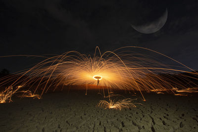 Firework display on beach against sky at night