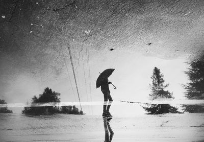Man standing on wet shore at beach against sky